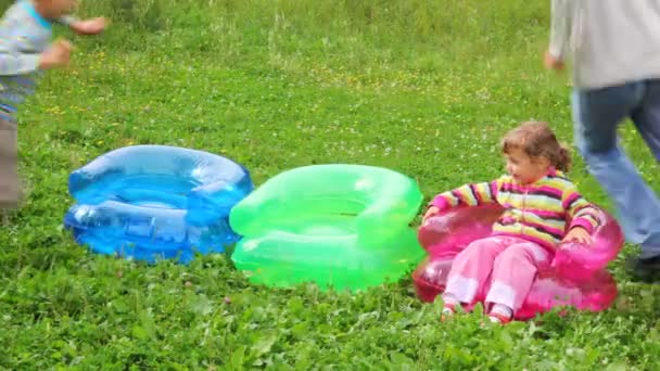 Family of three running around inflatable armchairs - Metraje, vídeo