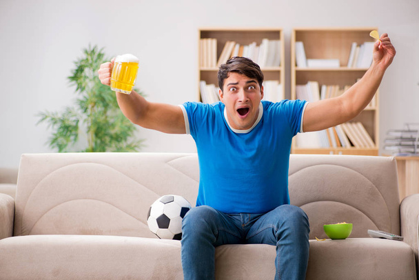 Mężczyzna ogląda piłkę nożną w domu siedzi na kanapie - Zdjęcie, obraz