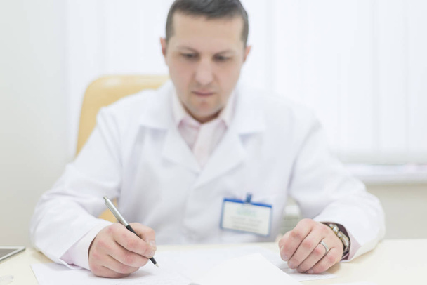 Doctor writes on a desk in the office - Photo, Image