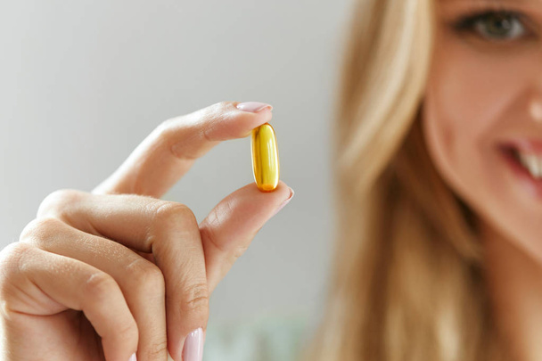 Beautiful Woman Holding Fish Oil Pill In Hand. Healthy Nutrition - Foto, imagen