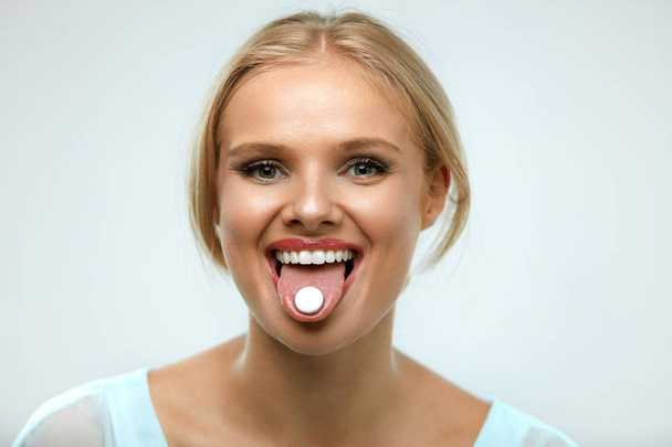 Bella donna sorridente che prende la medicina, tenendo pillola sulla lingua
 - Foto, immagini