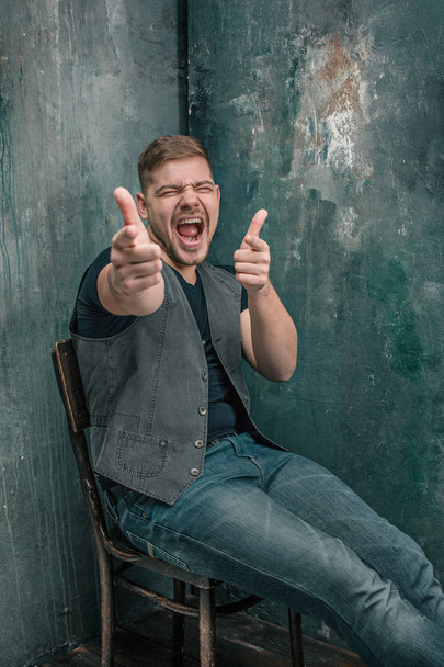 Portrait of smiling happy man sitting on the chair in studio - Fotografie, Obrázek
