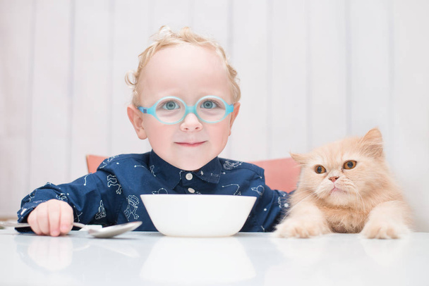 enfant portant des lunettes assis à table avec chat
 - Photo, image