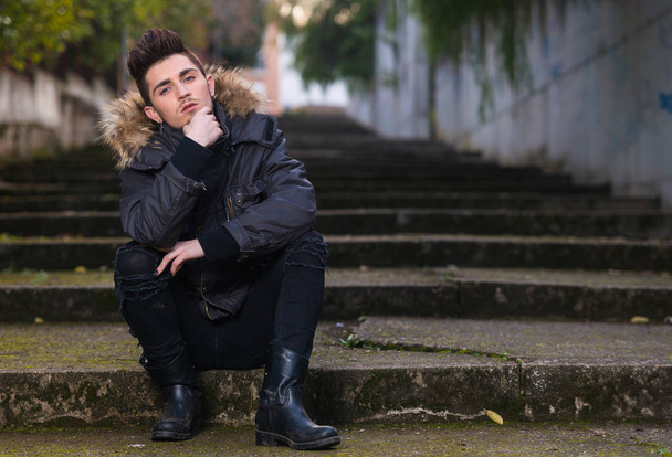 Young beautiful man, sitting on the street , looking at camera - Photo, Image