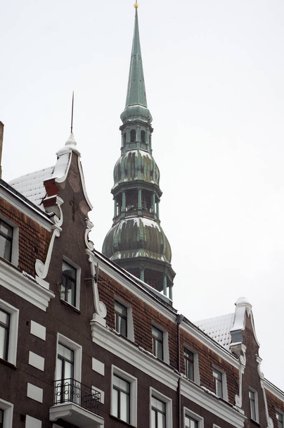 Spire of St Peter's cathedral behind old building facade in Riga, Latvia - Foto, Imagem