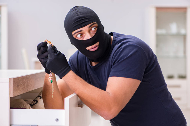 Robber wearing balaclava stealing valuable things - Foto, Imagen