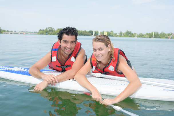 young couple swiming with paddle board in a lake - Foto, afbeelding