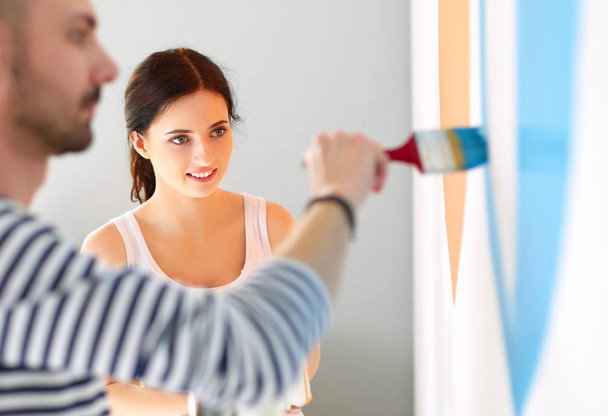 Portrait happy smiling young couple painting interior wall of new house - 写真・画像