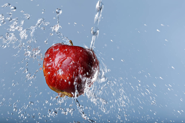 punainen omena vesipisaroissa sinisellä pohjalla
 - Valokuva, kuva
