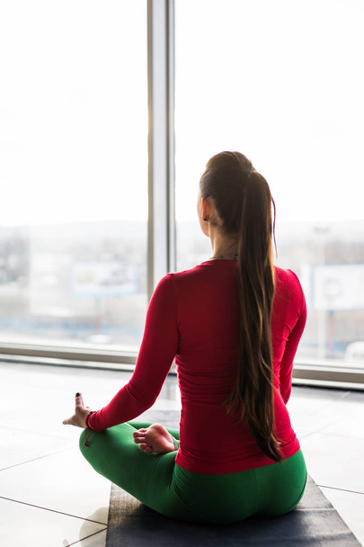 schöne Yoga-Frau mit Weihnachtsmütze praktiziert Yoga-Posen auf grauem Hintergrund.  - Foto, Bild