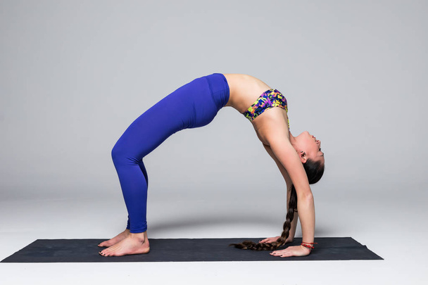 Beautiful yoga woman practice yoga poses on grey background. - Photo, Image