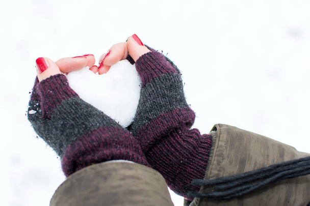 Woman hands holding heart shaped snowball - 写真・画像