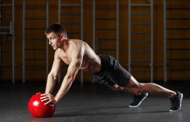 Muscular man doing sport exercises with red medicine ball. - Fotoğraf, Görsel