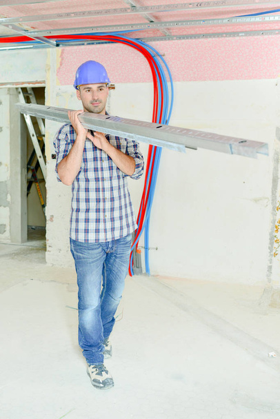 Builder carrying metal joists - Photo, Image