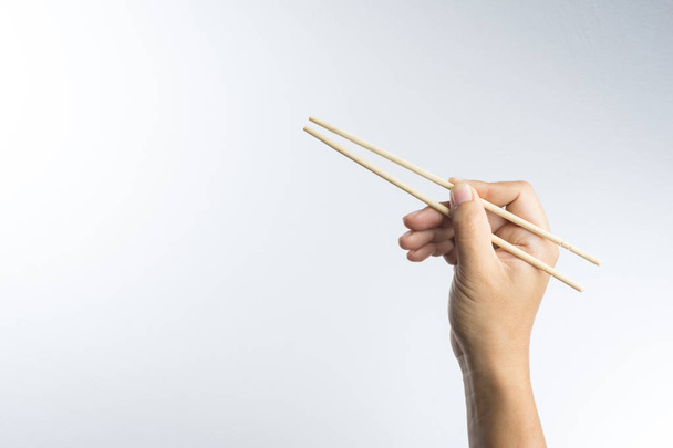Hand holding disposable wooden chopsticks made of bamboo - Fotó, kép