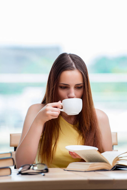 Junge Studentin bereitet sich auf Prüfungen vor und trinkt Tee - Foto, Bild