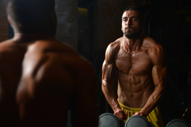 Hombre atlético mostrando sus músculos en el gimnasio
 - Foto, Imagen