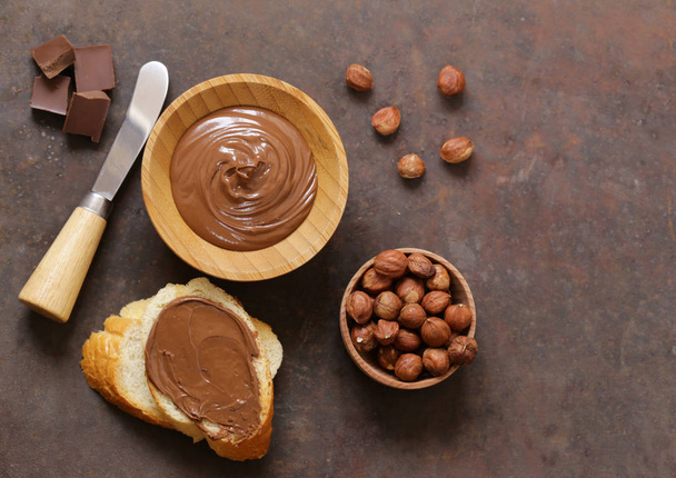 Suklaatahna levitetään hasselpähkinöiden ja leivän kanssa aamiaiseksi
 - Valokuva, kuva