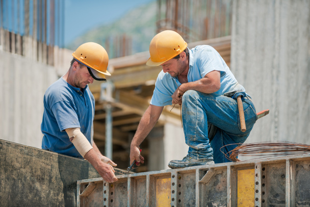 Deux travailleurs de la construction installant des coffrages en béton
 - Photo, image