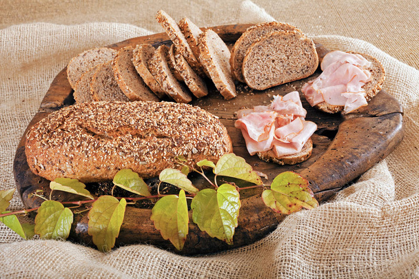integral bread on the wood board with ham and green branch, note shallow depth of field - Photo, Image
