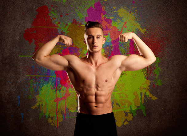 Strong guy with colorful paint wall and weight - Photo, Image