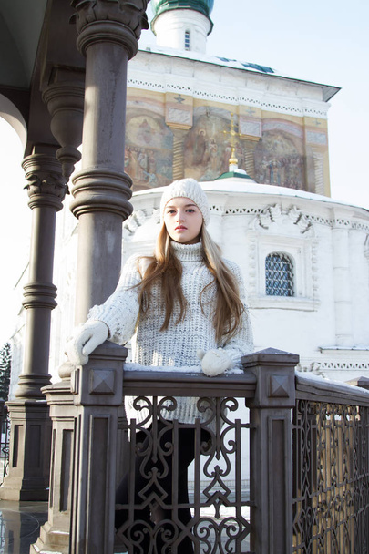 giovane ragazza in maglione e cappello a maglia sullo sfondo della chiesa. Ritratto invernale
 - Foto, immagini