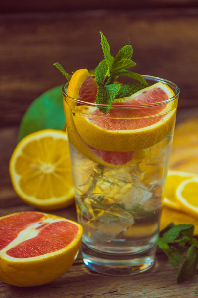 Fresh lemonade in a glass beaker with ice, green mint, red orang - Photo, Image