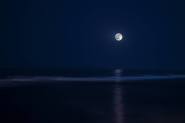 Πανσέληνος στον ουρανό νύχτας πάνω από φεγγαρόφωτο νερό - Φωτογραφία, εικόνα