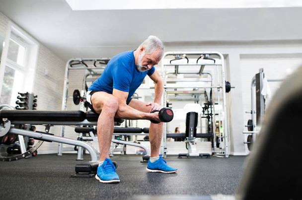 Senior man in gym working out with weights. - Φωτογραφία, εικόνα