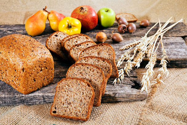 ржаной хлеб с семенами на деревянной доске с медовухой и фруктами вокруг
 - Фото, изображение