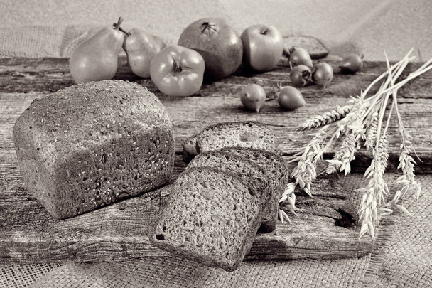 pain de seigle avec des graines sur une planche de bois avec un medlar et des fruits autour
 - Photo, image