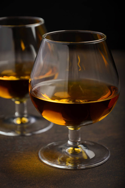 Glass of brandy or cognac on the old rusty background - 写真・画像
