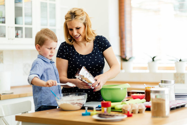 child helping mother in kitchen - Фото, зображення