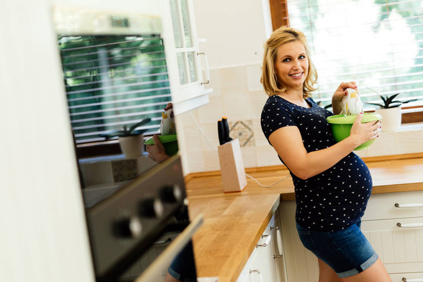 Pregnant woman working in kitchen - Zdjęcie, obraz
