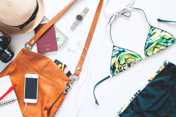 Flat lay set of summer items. Girl items with bikini, watch, mobile phone, camera and passport for summer vacation on white background - Foto, immagini