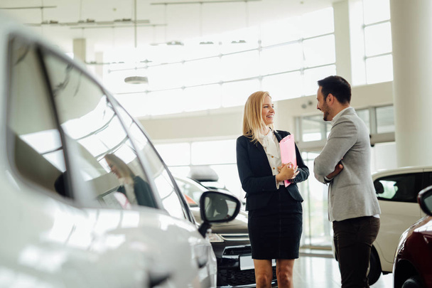 Salesperson selling cars at dealership - Foto, afbeelding