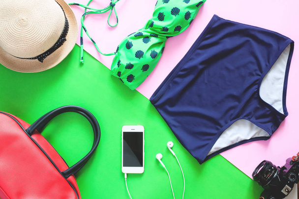 Lapos készlet nyáron tételeket feküdt. Zöld színű bikini-a mozgatható telefon és vonatkozó nyaralás, zöld és rózsaszín háttér - Fotó, kép
