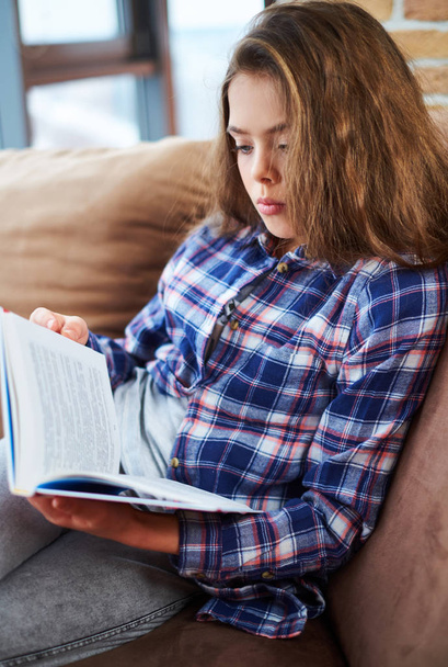 Menina bonita lendo livro em um sofá
 - Foto, Imagem