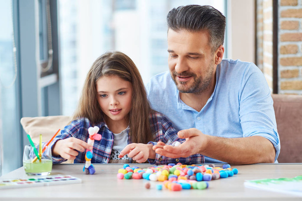 Beautiful little girl with her father playing with colored set for creativity - Photo, Image