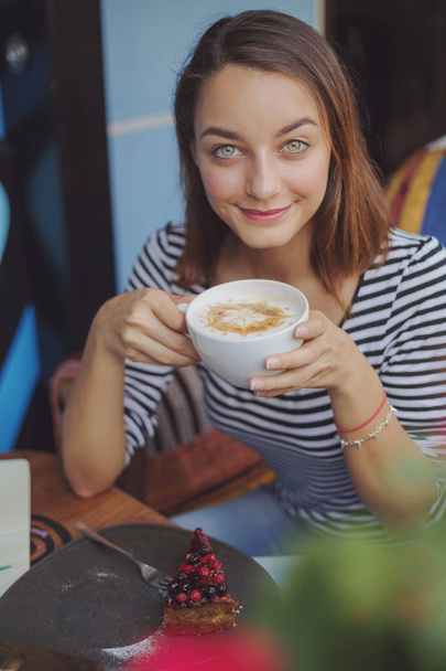 Nuori nainen istuu sisällä kaupunkien kahvilassa
 - Valokuva, kuva