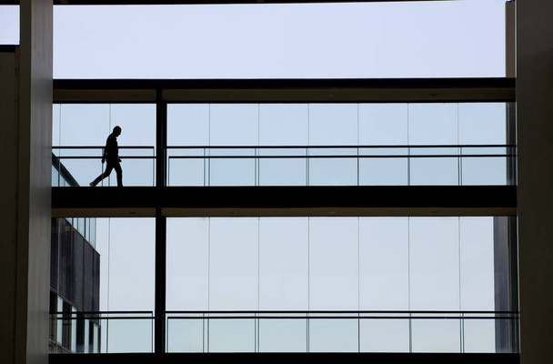 Silhouettenaufnahme eines jungen Geschäftsmannes in einem modernen Bürogebäude - Foto, Bild