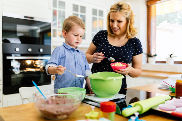 Smart cute child helping mother in kitchen - Foto, afbeelding