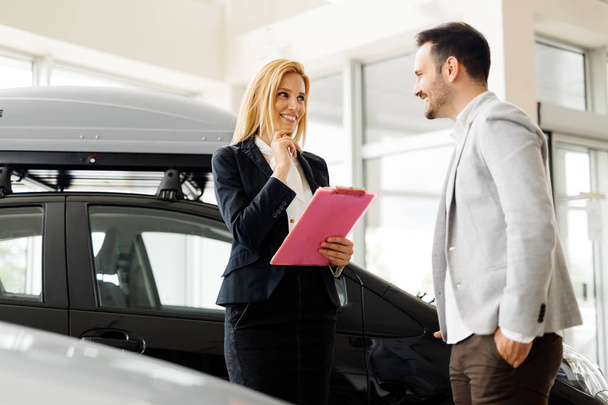 Salesperson selling cars at dealership - Foto, imagen