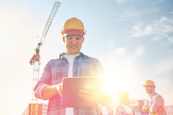builder in hardhat with tablet pc at construction - Фото, зображення