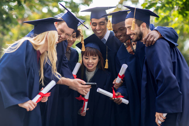 estudiantes o solteros con diplomas y teléfonos inteligentes
 - Foto, Imagen