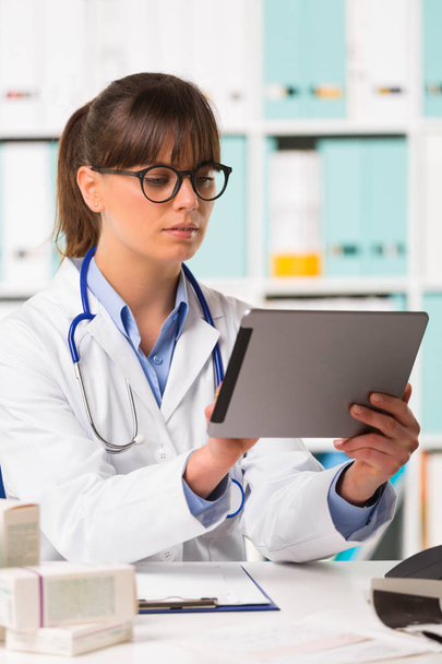 Düşünceli kadın doktor masada tablet kullanma - Fotoğraf, Görsel
