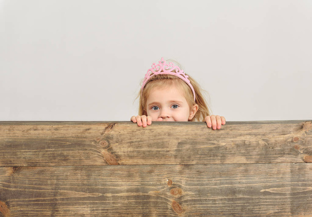 Cute girl peeping over wooden border - Zdjęcie, obraz