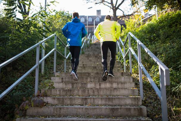 Two athletes running on stairs in sunny autumn, rear view. - Foto, Imagem