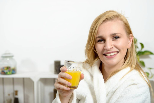 kaunis nuori blondi nainen juo appelsiinimehua
 - Valokuva, kuva