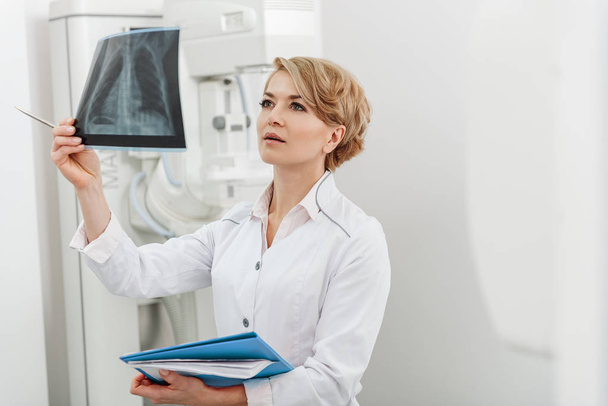 Interested female doctor holding radiograph - Zdjęcie, obraz